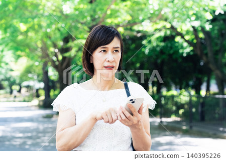 拿著智慧型手機思考的中年婦女 140395226