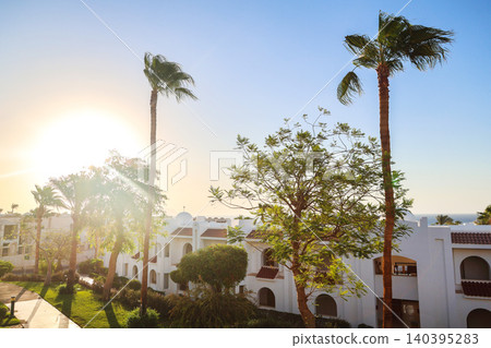Classic resort in an Arab country with white buildings, palm trees, and serene coastal architecture under clear blue sky 140395283