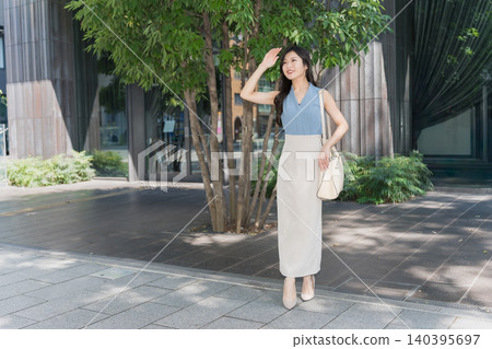 A businesswoman in the office district smiles and raises her hand. A businesswoman in the office district smiles and raises her hand. 140395697