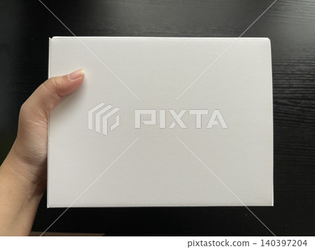 Hand Holding White Cardboard Box on Dark Wood Hand Holding White Cardboard Box on Dark Wood 140397204