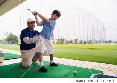Golf instructor teaching young student proper swing at driving range Golf instructor teaching young student proper swing at driving range 140397401