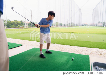Golf instructor teaching young student proper swing at driving range 140397402