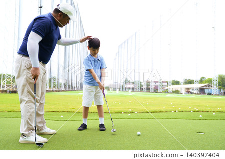 Golf instructor teaching young student to putt at practice green Golf instructor teaching young student to putt at practice green 140397404