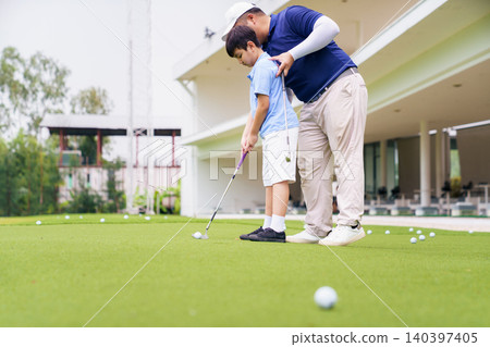 Golf instructor teaching young student to putt at practice green Golf instructor teaching young student to putt at practice green 140397405
