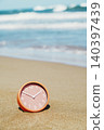 a clock rests in the sand at an empty beach 140397439