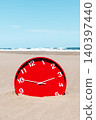 a red clock on a broad deserted beach 140397440
