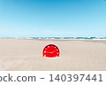 a red clock emerges from the sand on a beach 140397441