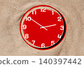 a red clock is nearly buried beneath fine sand 140397442