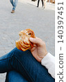 a man holds a bitten kanelbulle in a public square 140397451