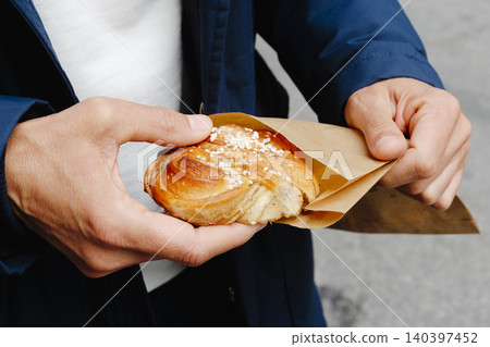 a man unwraps a swedish kanelbulle a man unwraps a swedish kanelbulle 140397452