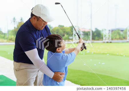 Golf instructor teaching young student proper swing at driving range Golf instructor teaching young student proper swing at driving range 140397456