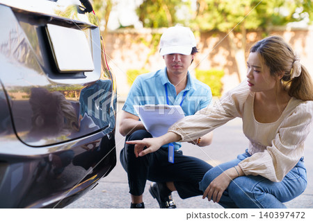 Insurance agent and woman inspecting car damage after accident Insurance agent and woman inspecting car damage after accident 140397472
