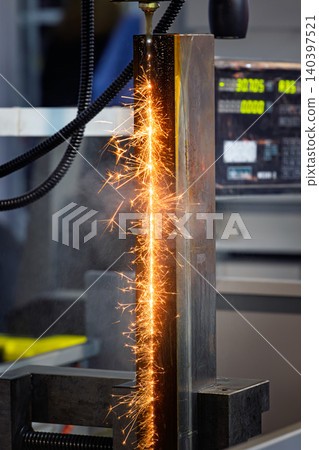 Wire EDM cutting of metal workpiece with sparks in industrial machine. 140397521