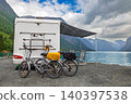 Camper van with bicycles parked by fjord in mountain landscape. 140397538