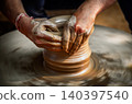 Skilled artisan hands shaping wet clay on a spinning potter wheel, creating a ceramic vase in a traditional pottery workshop. 140397540