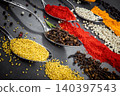 Collection of spices are spread out on a table. The spices include cumin, paprika, and turmeric 140397543