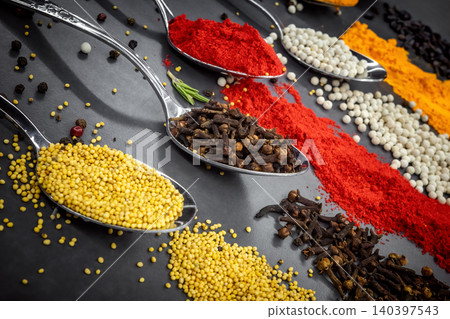 Collection of spices are spread out on a table. The spices include cumin, paprika, and turmeric Collection of spices are spread out on a table. The spices include cumin, paprika, and turmeric 140397543