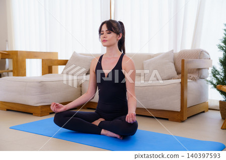 Young woman in meditation pose on blue yoga mat 140397593