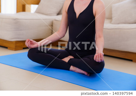 Young woman in meditation pose on blue yoga mat Young woman in meditation pose on blue yoga mat 140397594