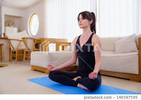 Young woman in meditation pose on blue yoga mat 140397595