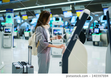 Asian woman using airport self service check in kiosk 140397894