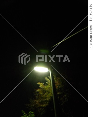 The streetlights at night and the trees illuminated in the darkness The streetlights at night and the trees illuminated in the darkness 140398319