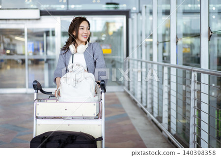 Happy Asian woman pushing luggage cart at airport terminal 140398358
