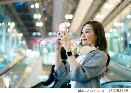 Young Asian woman traveling on escalator at airport terminal Young Asian woman traveling on escalator at airport terminal 140398369