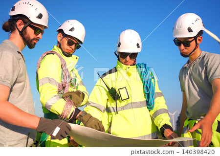 Engineers discussing a blueprint plan at a wind turbine farm Engineers discussing a blueprint plan at a wind turbine farm 140398420