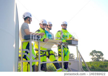 Engineers discussing a blueprint plan at a wind turbine farm Engineers discussing a blueprint plan at a wind turbine farm 140398422