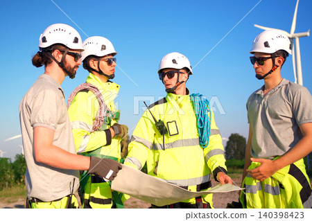 Engineers discussing a blueprint plan at a wind turbine farm Engineers discussing a blueprint plan at a wind turbine farm 140398423