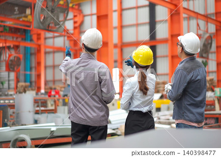 Asian engineers explaining factory machinery operations to a client 140398477