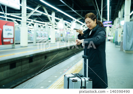 Asian woman using mobile phone while waiting at train station Asian woman using mobile phone while waiting at train station 140398490