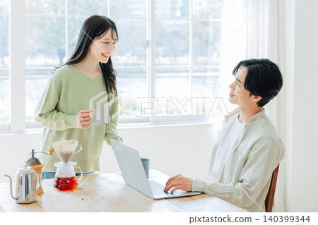 A woman makes coffee for a man while he's working. A woman makes coffee for a man while he's working. 140399344
