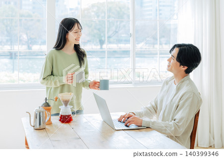 A woman makes coffee for a man while he's working. A woman makes coffee for a man while he's working. 140399346