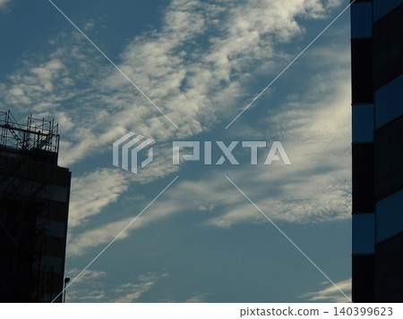 卷積雲和藍天鋪滿了城市上空,夾在建築物之間。 卷積雲和藍天鋪滿了城市上空,夾在建築物之間。 140399623