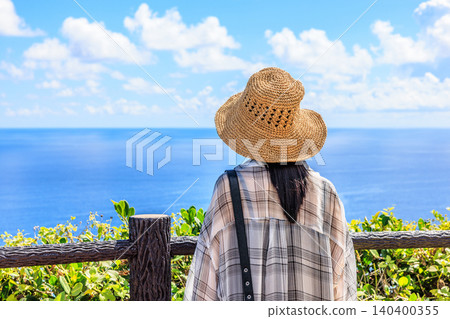 A woman wearing a straw hat; outdoors; beach; summer image. A woman wearing a straw hat; outdoors; beach; summer image. 140400355