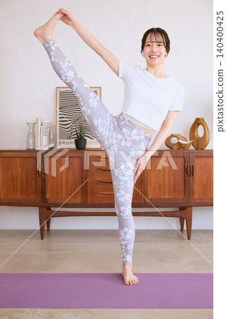 A smiling young woman doing yoga poses at home. A smiling young woman doing yoga poses at home. 140400425