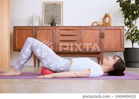 A woman doing pelvic exercises at home using a balance ball. A woman doing pelvic exercises at home using a balance ball. 140400428
