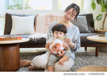 A smiling mother brushes her child's teeth in the living room. A smiling mother brushes her child's teeth in the living room. 140400580