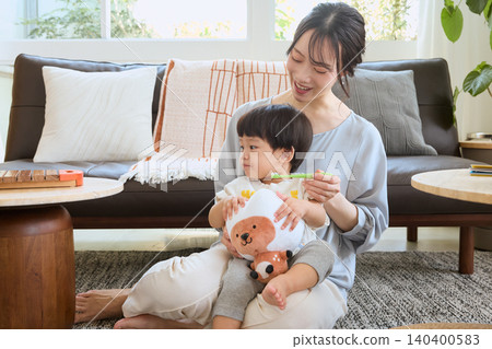 A smiling mother brushes her child's teeth in the living room. A smiling mother brushes her child's teeth in the living room. 140400583