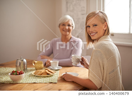 Portrait, happy woman and elderly mother drinking tea at breakfast, bonding and smile in house. Face, senior mom and daughter with coffee cup at table, food and family eating cookies at home together Portrait, happy woman and elderly mother drinking tea at breakfast, bonding and smile in house. Face, senior mom and daughter with coffee cup at table, food and family eating cookies at home together 140400679