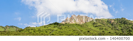 Scenic panoramic view of rolling green hills under a blue cloudy sky Scenic panoramic view of rolling green hills under a blue cloudy sky 140400700