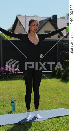 Vertical video. Young beautiful sports girl in leggings does exercises with dumbbells. Healthy lifestyle. Woman goes in for sports outdoor at home. 140400862