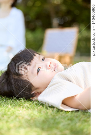 A pensive toddler leaning against the green grass. A pensive toddler leaning against the green grass. 140400906