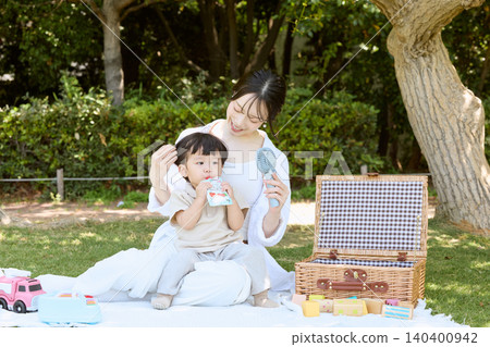 A mother and her young son enjoying a picnic in the park. A mother and her young son enjoying a picnic in the park. 140400942
