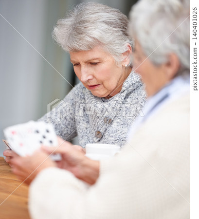 Senior women, thinking and playing cards with game for friends in retirement, relax and bonding together. Elderly people, poker and strategy with serious fun at table in nursing home for weekend. Senior women, thinking and playing cards with game for friends in retirement, relax and bonding together. Elderly people, poker and strategy with serious fun at table in nursing home for weekend. 140401026