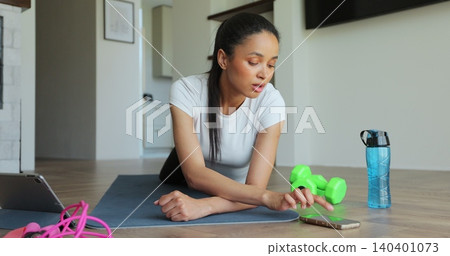 Sporty woman in sportswear doing plank while watching training video on tablet. Watching online fitness training lessons. Sporty woman in sportswear doing plank while watching training video on tablet. Watching online fitness training lessons. 140401073