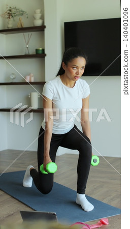 Vertical video. Athletic young woman in sportswear training at home, performing squats with dumbbells in her hands, enjoying a healthy lifestyle. Athletic woman doing training. Vertical video. Athletic young woman in sportswear training at home, performing squats with dumbbells in her hands, enjoying a healthy lifestyle. Athletic woman doing training. 140401096