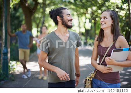 Students, friends and talking of college on campus for learning, knowledge and happy conversation. Young people laughing, smile and discussion of scholarship, study or education at park or university 140401153